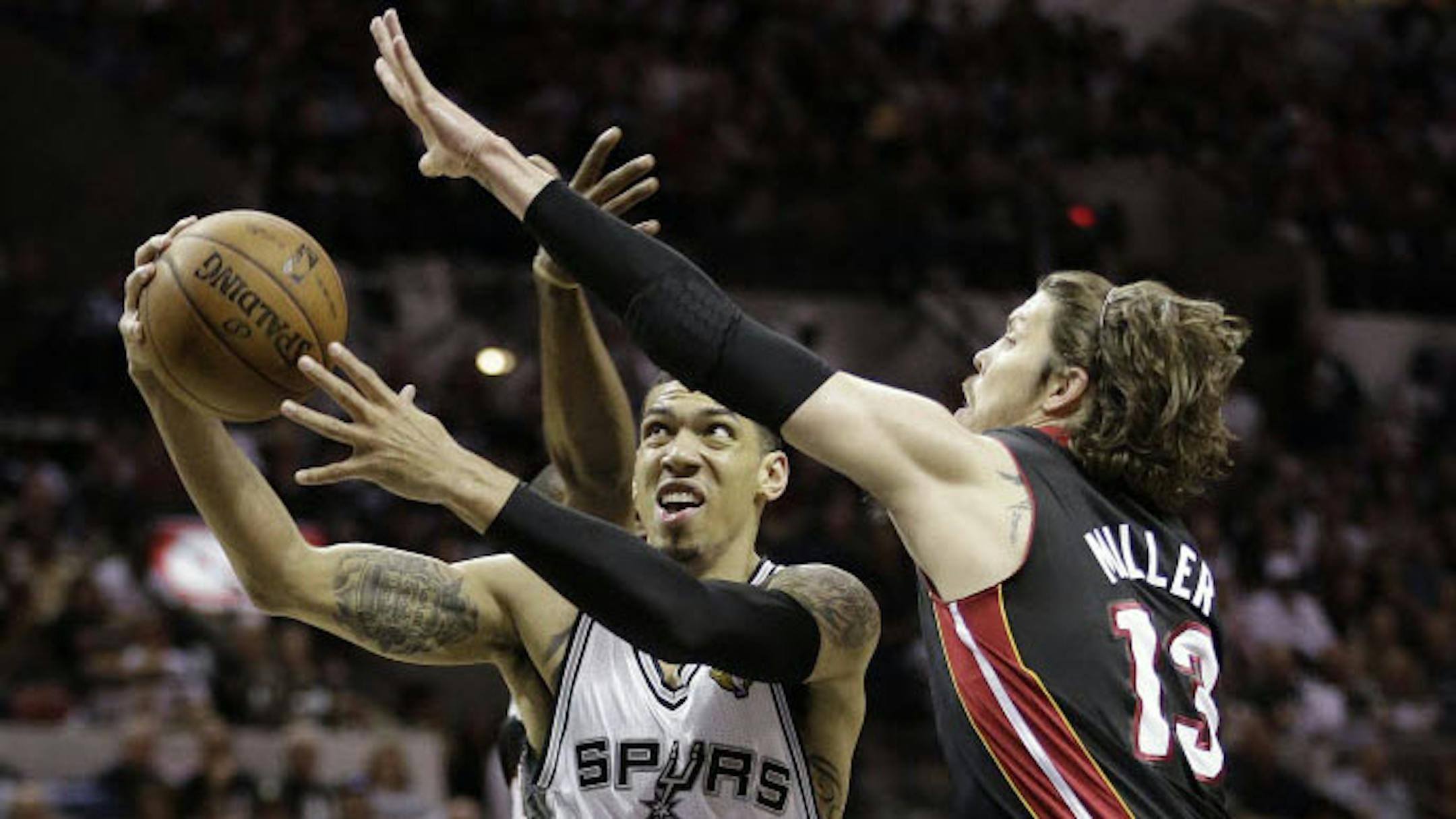 San Antonio Spurs' Danny Green (4) shoots between Miami Heat's Mario Chalmers, rear, and Mike Miller (13).