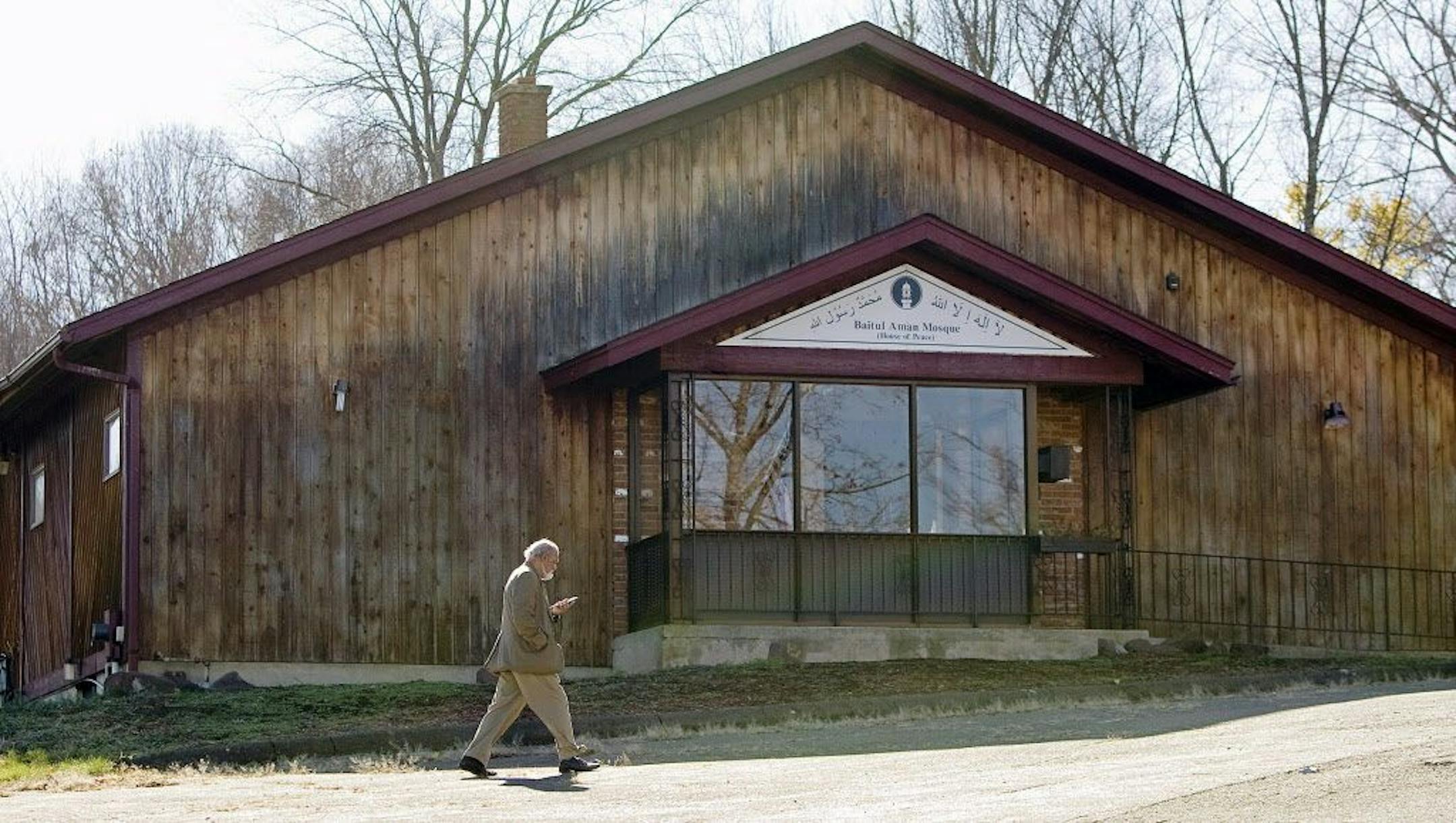 In this Tuesday, Nov. 17, 2015 photo, a member of the Ahmadiyya Muslim Community of Connecticut walks past the Baitul Aman mosque in South Meriden, Conn., where police and the FBI had been investigating reports of multiple gunshots fired at the mosque during the weekend.