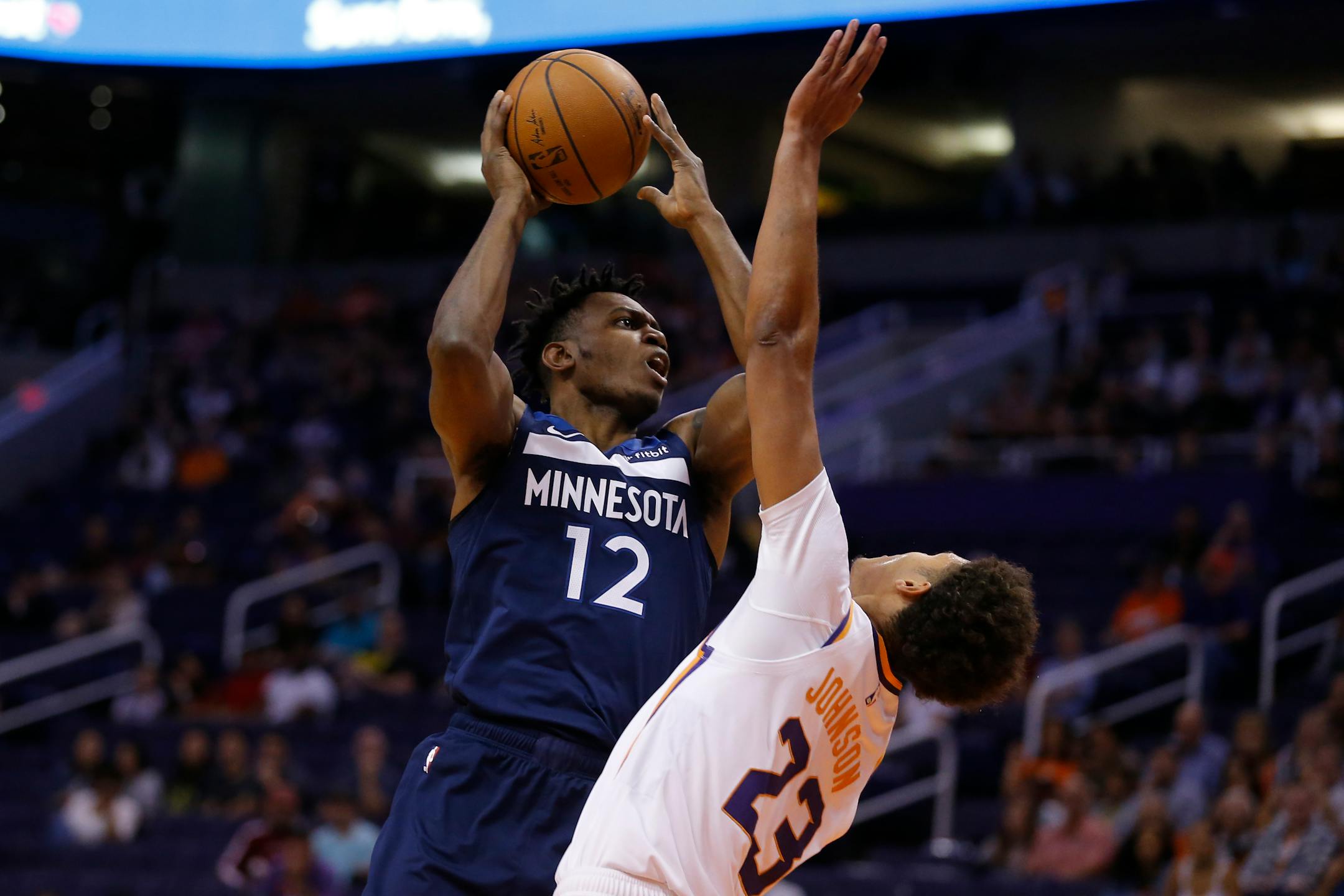 Minnesota Timberwolves guard Treveon Graham (12) shoots over Phoenix Suns forward Cameron Johnson in the first half during a preseason NBA basketball game, Tuesday, Oct. 8, 2019, in Phoenix. (AP Photo/Rick Scuteri)
