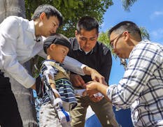 Mechanical engineering students Ethan Jen, left, and Marcos Serrano, center, put on a custom motorized orthotic brace that they and a group of fellow 