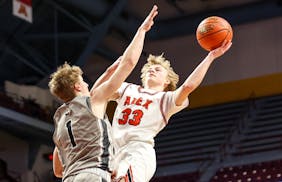 Alexandria’s Mason Witt put up a shot against Mankato East’s Giles Lancaster during Alexandria’s 62-57 win. 