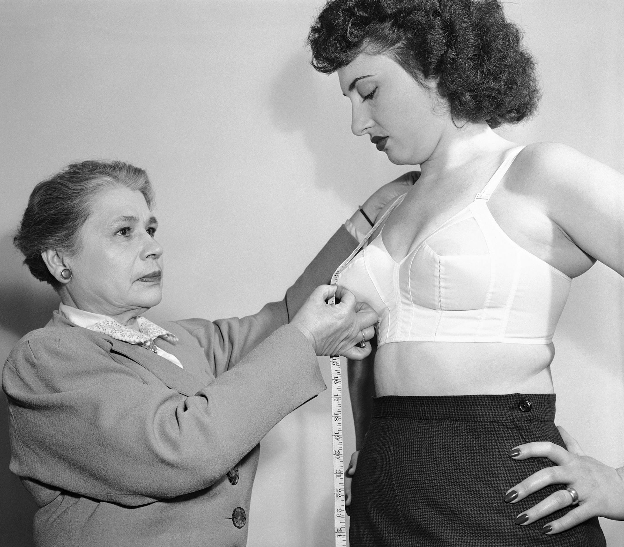 Mrs. Ida Rosenthal, left, an authority on the subject of brassieres, measures a model for a bra, measuring from the shoulder blade to mid-breast in New York, Nov. 20, 1950. Mrs. Rosenthal says the correct elevation for the natural bosom look is about ten inches from the shoulder line, less for for short women, more for tall ones. She and her husband head a large New York Brassiere firm. (AP Photo/Bob Wands) ORG XMIT: APHS102279