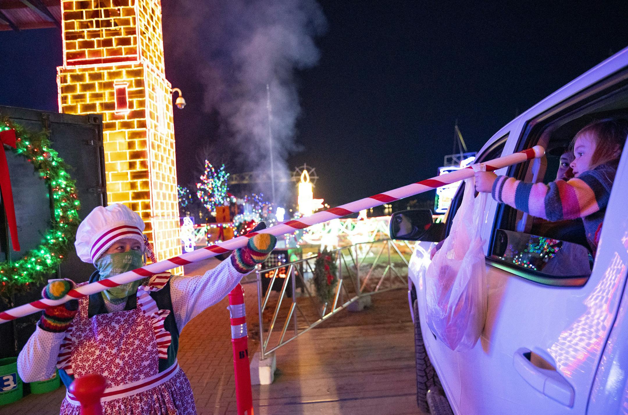 Diana Kiesow handed Aubrey Purtle, 3, from Elk River, Minn., a bag of Bentleyville knit hats using a 6-foot-long candy cane pole on Saturday.