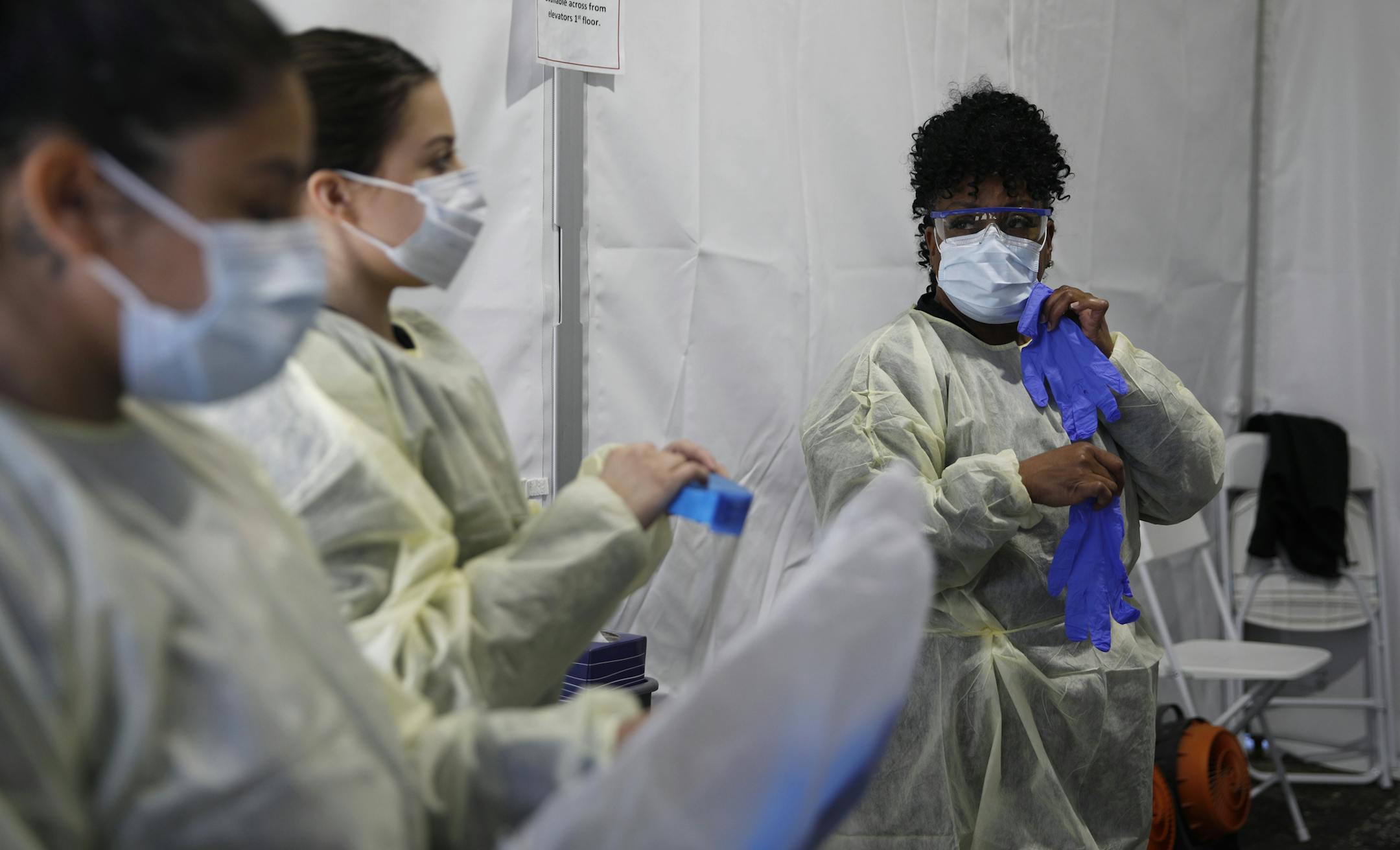 Health care workers with the UNLV School of Medicine suit up in personal protective equipment before taking patients at a drive thru coronavirus testing site Tuesday, March 24, 2020, in Las Vegas. UNLV Medicine, the clinical arm of the UNLV School of Medicine, started conducting COVID-19 testing by appointment for people who meet the Centers for Disease Control and Prevention guidelines. (AP Photo/John Locher)