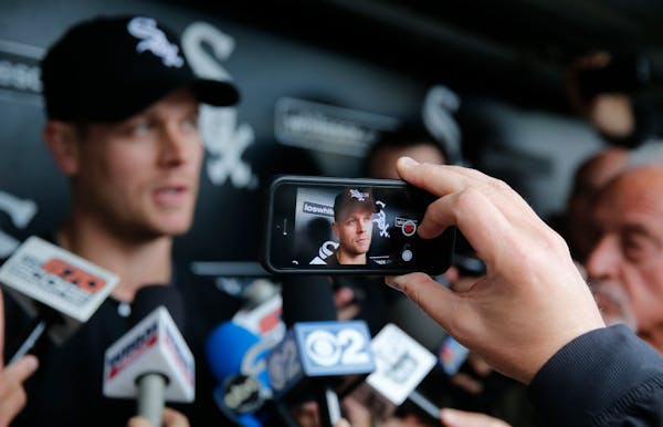 Justin Morneau is displayed on a mobile device as he talks with reporters before an interleague baseball game against Washington Nationals.