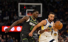 Warriors guard Stephen Curry drives while defended by Wolves guard Anthony Edwards in the second quarter Sunday night at Target Center.