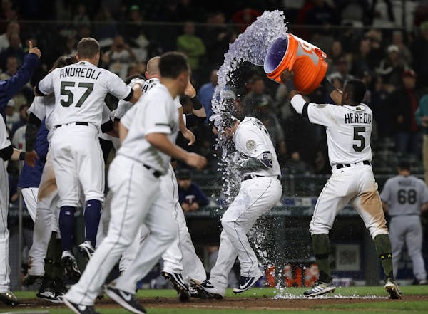Seattle Mariners Mike Zunino, second from right, is doused with sports drink by teammate Guillermo Heredia, right, after Zunino hit a walk-off solo ho