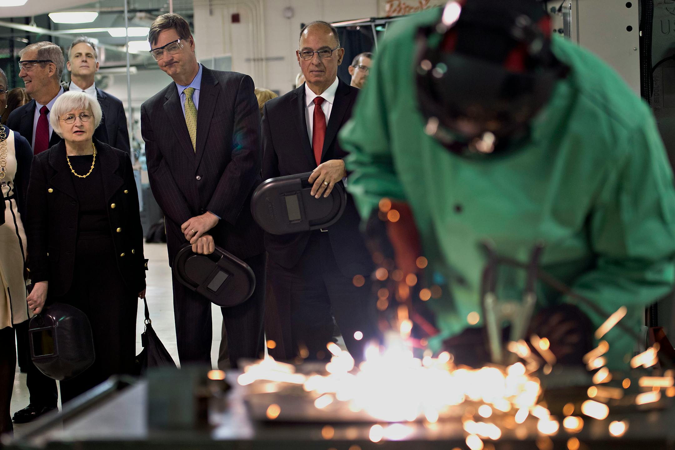 Janet Yellen, chair of the U.S. Federal Reserve, left, and Charles Plosser, chairman of the Federal Reserve Bank of Chicago, second from left, look on as a student uses a cutting torch in the manufacturing lab at Daley College in Chicago, Illinois, U.S., on Monday, March 31, 2014. Yellen said "considerable slack" in the labor market is evidence that the central bank�s unprecedented accommodation will still be needed for "some time" to combat unemployment. Photographer: Daniel Acker/Bloomberg ***