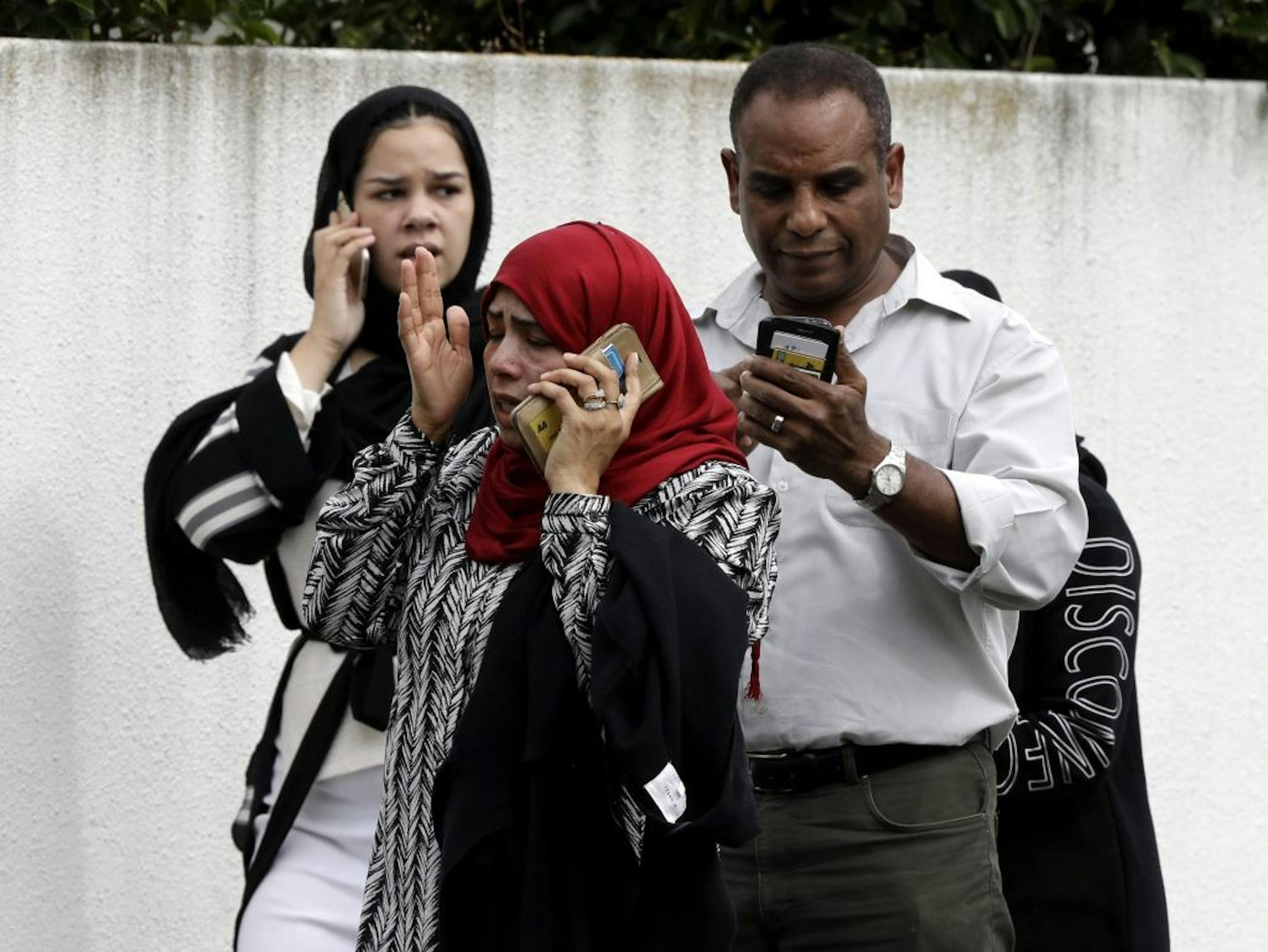 People wait outside a mosque in central Christchurch, New Zealand, Friday, March 15, 2019. Many people were killed in a mass shooting at a mosque in the New Zealand city of Christchurch on Friday, a witness said. Police have not yet described the scale of the shooting but urged people in central Christchurch to stay indoors.