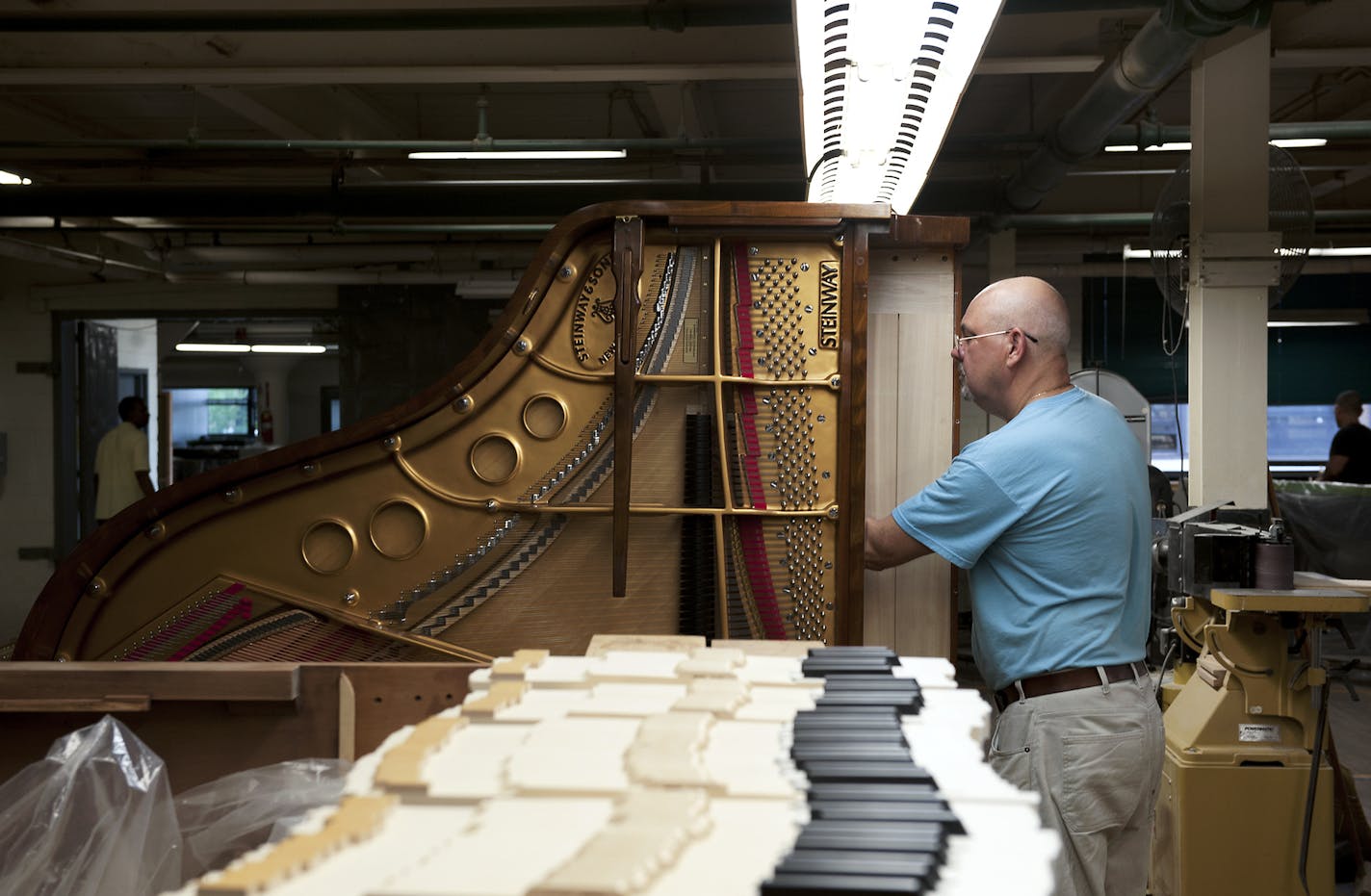 Edward Carrasco works on a Steinway piano at the Steinway factory in New York, July 9, 2013. With Steinway & Sons up for sale, pianists worry things just won't be the same.