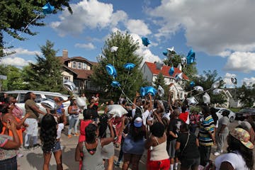 A group releases balloons into the air during a vigil for 28-year old Jaquan Oatis who was shot and killed in the Jordan neighborhood in north Minneap