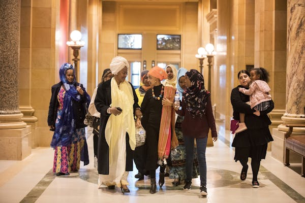 Rep. Ilhan Omar, DFL-Minneapolis, center, walks into the House Chambers with her family and friends for a ceremonial swearing in.