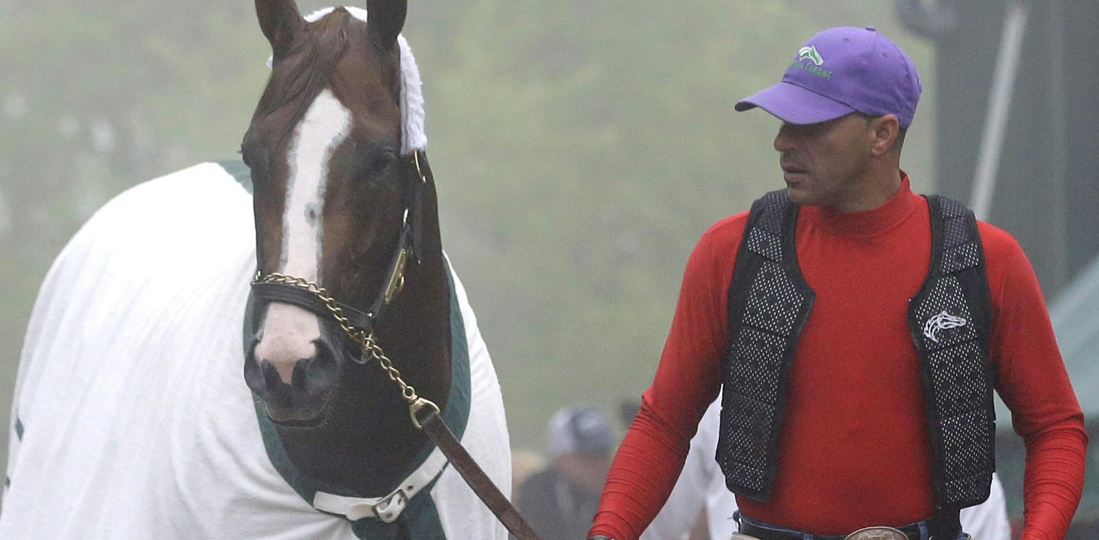 Exercise rider Willie Delgado, center, leads Kentucky Derby winner California Chrome to his stable as trainer Art Sherman, right, watches after a workout at Pimlico Race Course in Baltimore, Thursday, May 15, 2014. The Preakness Stakes horse race is scheduled to take place May 17. (AP Photo/Patrick Semansky)