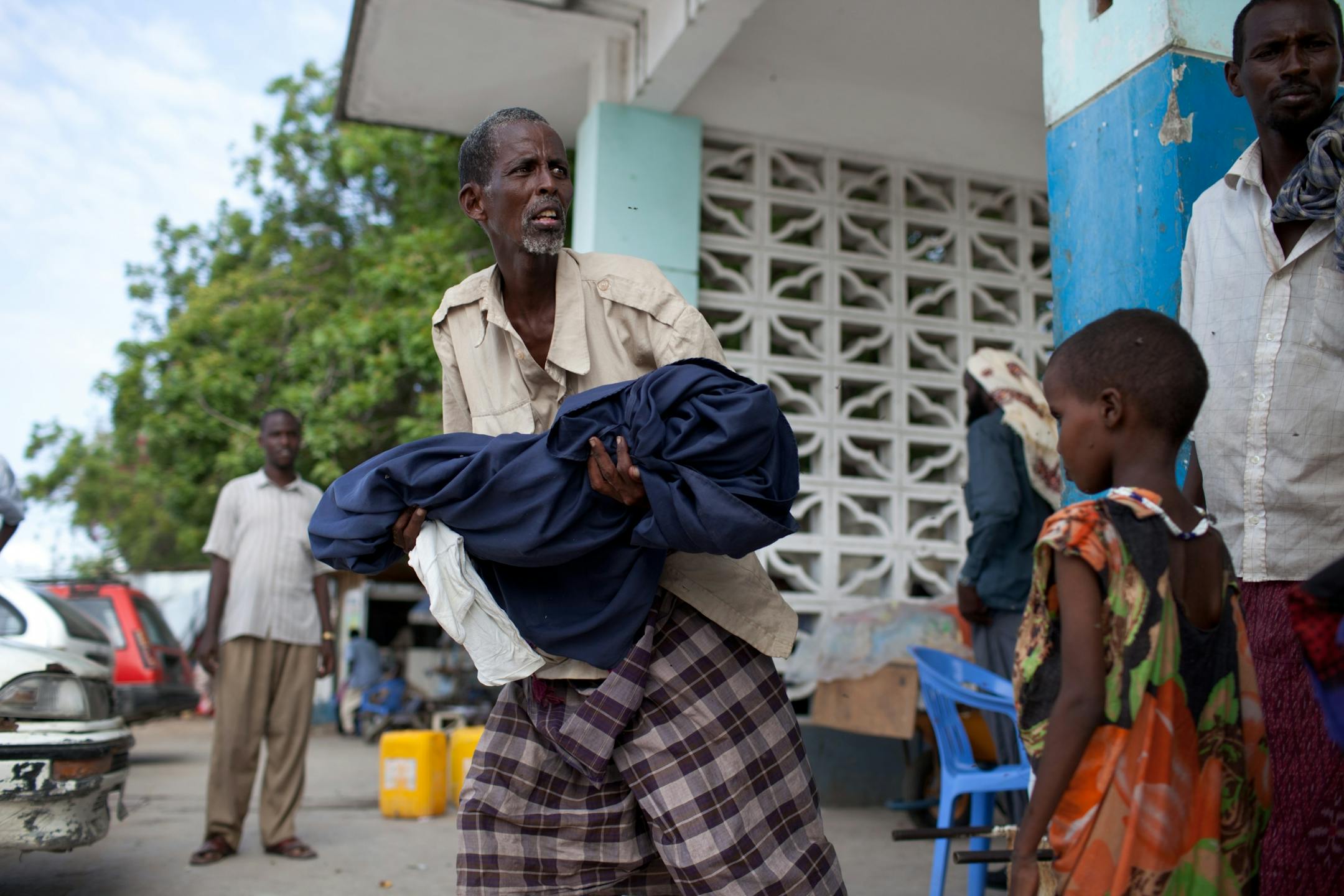 Kufow Ali Abdi carried the body of his 3-year-old daughter, Kadija, who had just died from measles at the hospital in Mogadishu, Somalia, on July 28. "I just hope they can save the others," he said, referring to his two remaining children, who were down to skin and bone. The al-Shabab Islamist insurgent group, which controls much of southern Somalia, is blocking starving people from fleeing the country and setting up a camp where it is imprisoning displaced people who were trying to escape al-Sh