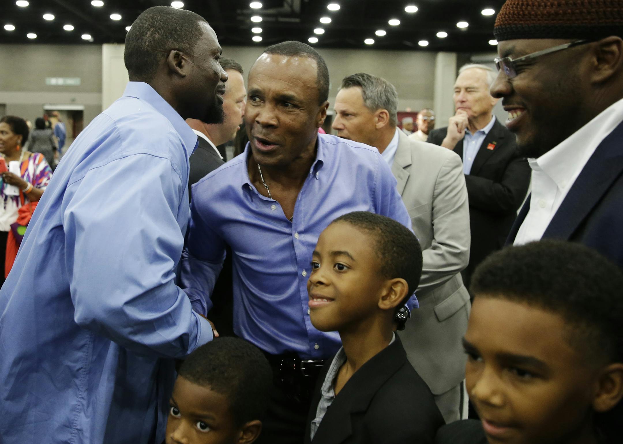 Former boxing champion Sugar Ray Leonard, center, is greeted by former two time heavyweight world champion Hasim Rahman before Muhammad Ali's Jenazah, a traditional Islamic Muslim service, in Freedom Hall, Thursday, June 9, 2016, in Louisville, Ky. (AP Photo/Darron Cummings)