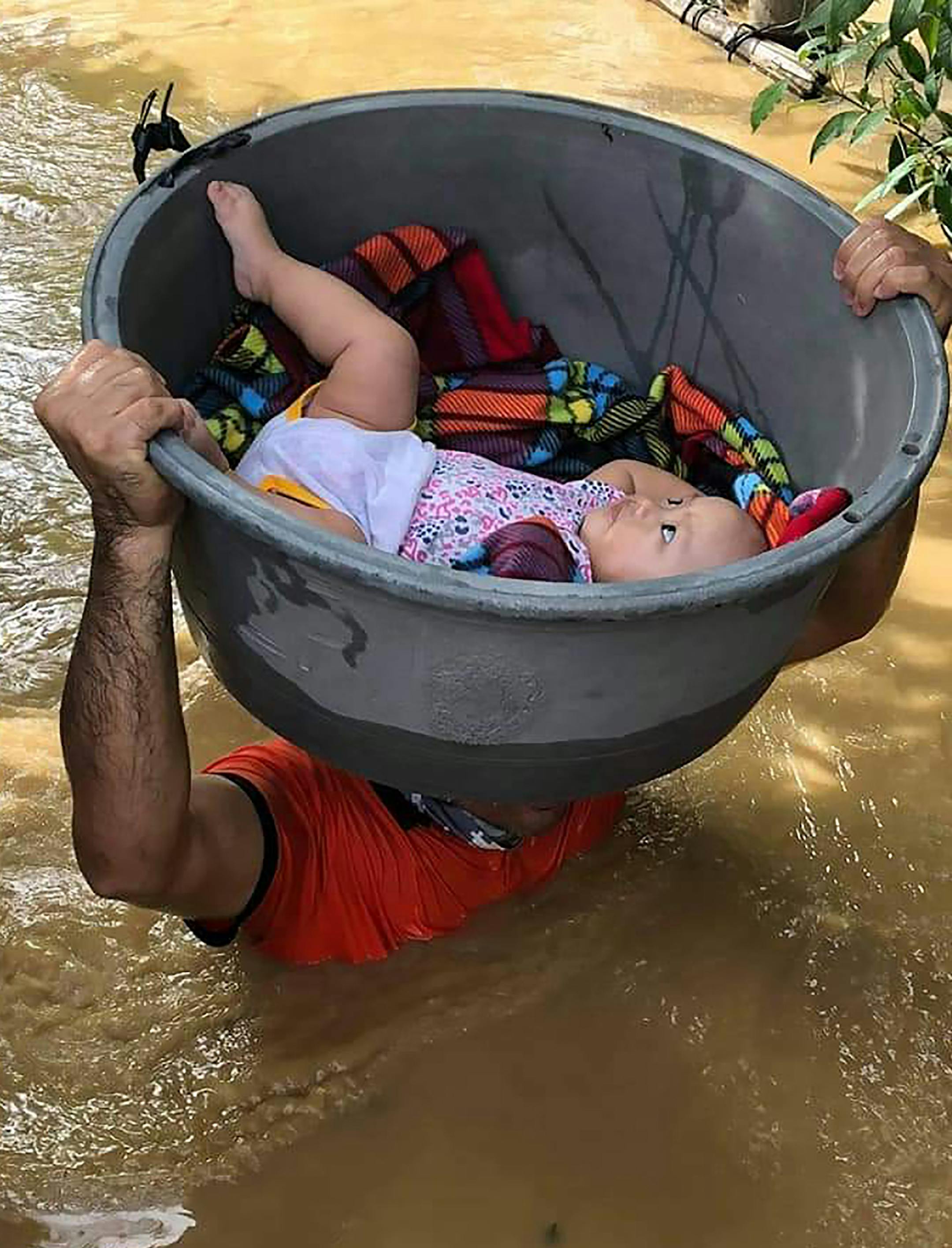In this photo provided by the Philippine Coast Guard, a baby is carried using a plastic container during rescue operations along a flooded village in the Cagayan valley region, northern Philippines on Friday Nov. 13, 2020. Thick mud and debris coated many villages around the Philippine capital Friday after Typhoon Vamco caused extensive flooding that sent residents fleeing to their roofs and killing dozens of people. (Philippine Coast Guard via AP)
