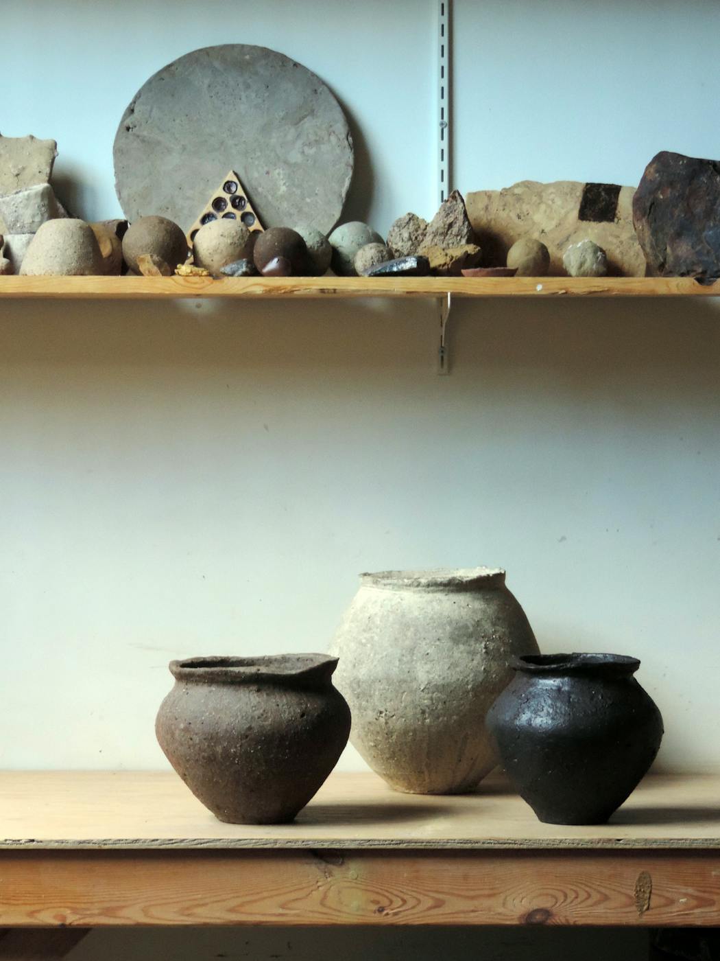 Finished vessels below a collection of raw materials and studies in Mitch Iburg’s studio.