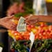 Person hands over money to buy produce at farmers market.