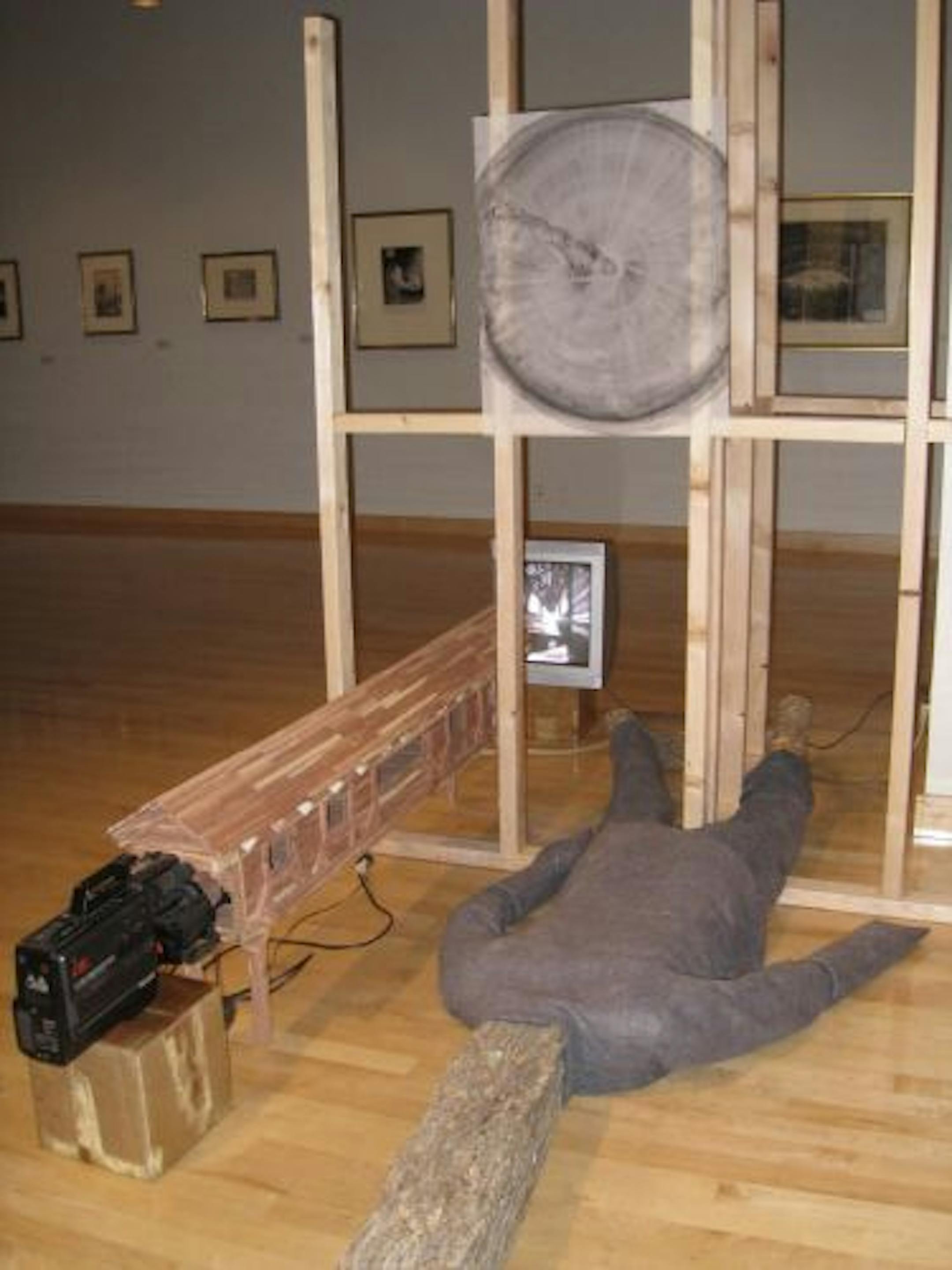 In an "Untitled" installation, Chris Larson combines his hallmark wood architectural frameworks with a live video feed and a gray wool felt suit.