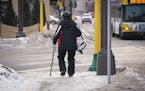 A pedestrian using a cane walked along an icy sidewalk along Central Avenue Northeast in Minneapolis.