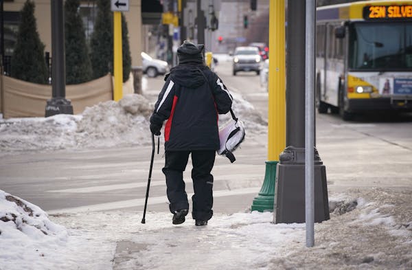 A pedestrian using a cane walked along an icy sidewalk along Central Avenue Northeast in Minneapolis.
