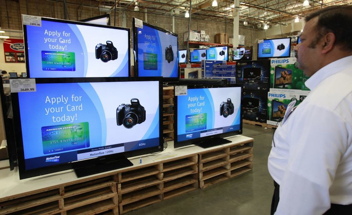 FILE - In this May 4, 2010 file photo, a customer looks at wide screen sets advertising American Express cards at a Costco store in Mountain View, Calif. Costco shoppers who have been limited for years to American Express credit cards may be able to pluck a new option from their wallets or purses next year when an exclusivity deal between the two companies expires on March 31, 2016.