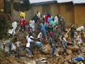 FILE- In this Tuesday, Aug.15, 2017 file photo, volunteers search for bodies from the scene of heavy flooding and mudslides in Regent, just outside of