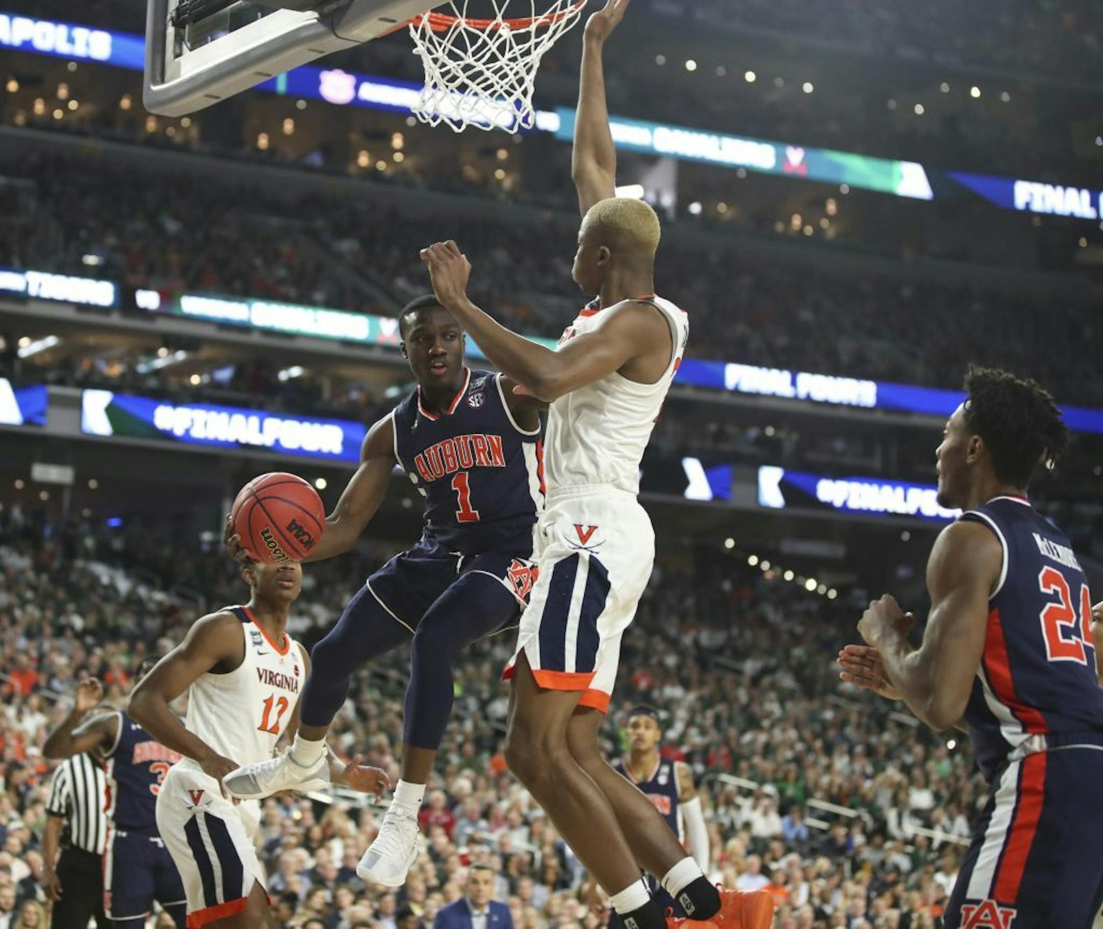 Auburn guard Jared Harper (1) passed around Virginia Cavaliers forward Mamadi Diakite (25) to teammate Anfernee McLemore (24) in the first half.