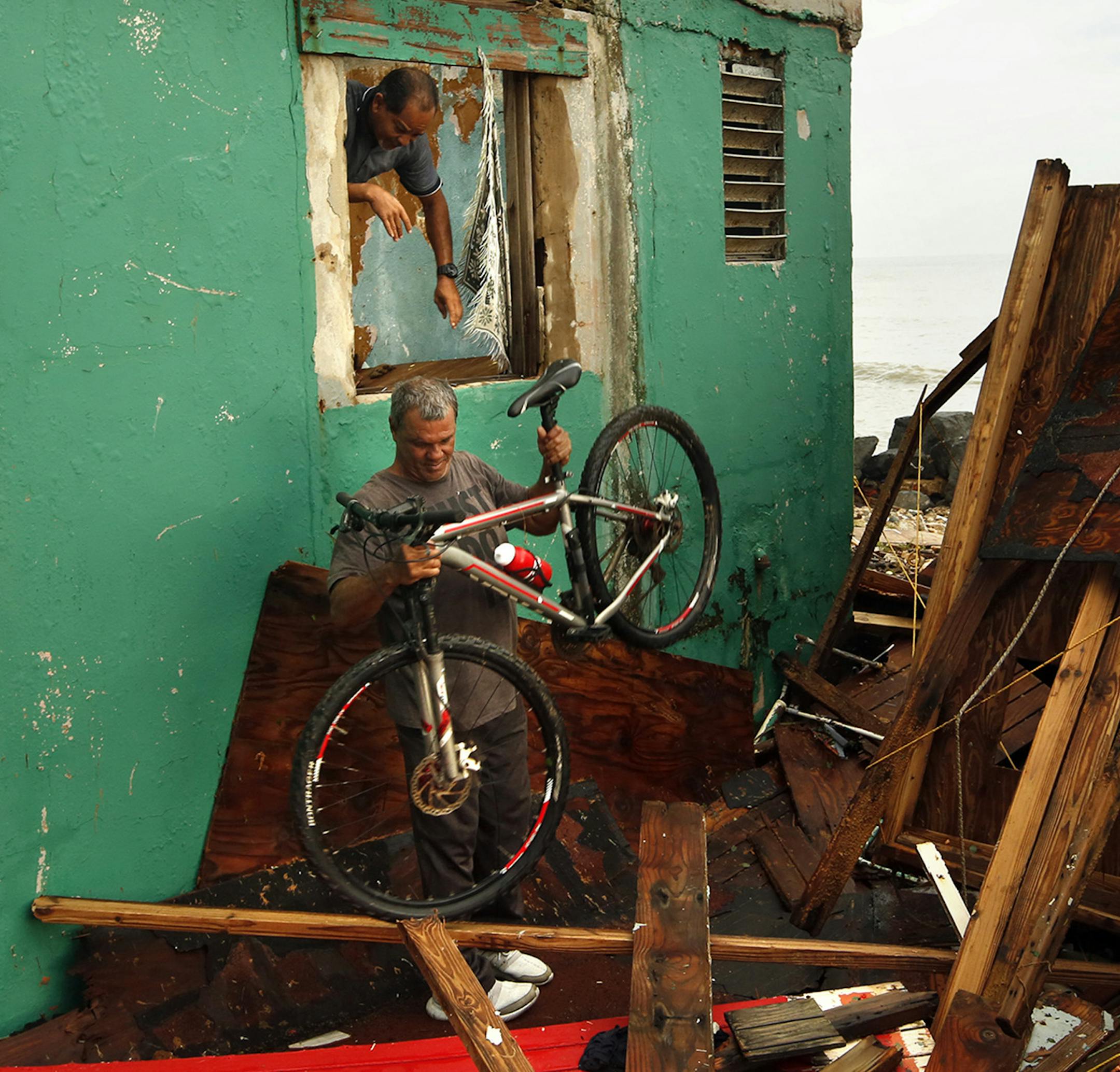 Ivan Lopez, 51, helps his neighbor with the damage to his neighbor's home on Sept. 21, 2017 in Puerto Rico. His home was not as badly damaged so he plans to stay despite the lack of water and electricity. "I was born here; I'll die here," said Lopez. (Carolyn Cole/Los Angeles Times/TNS) ORG XMIT: 1211595