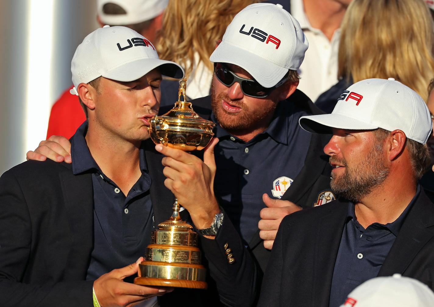 Jordan Spieth kisses the Ryder Cup with teammates JB Holmes and Ryan Moore.