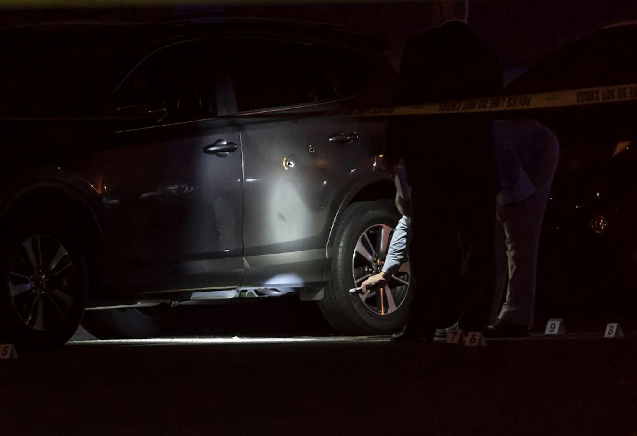 Investigators looked at what appeared to be bullet holes in a car door the scene of a homicide in St. Paul, Minn., on Wednesday, September 18, 2019.