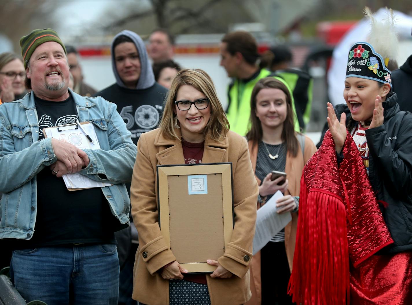 Lt. Gov. Peggy Flanagan, walks to the stage as Robert Lilligren, executive director of Minneapolis' Native American Community Development Institute, left, and Tracy Menard, 13, Miss Minneapolis Indian Community, right, cheer her on during the Kick-Off Day that commemorates May as Minnesota American Indian Month and seen Wednesday, May 1, 2019, at Little Earth in Minneapolis, MN.