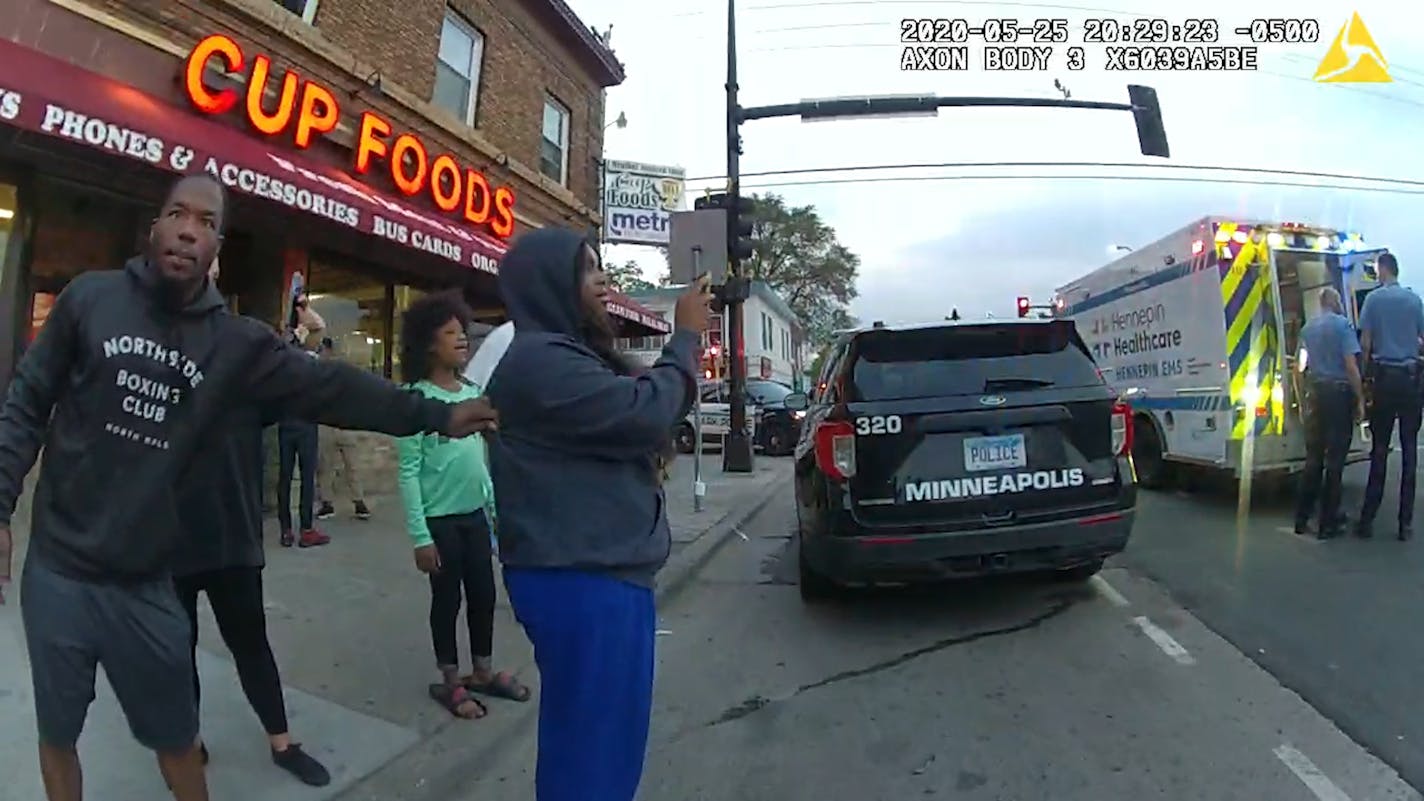 A screenshot from ex-officer Tou Thao's body camera shows bystanders look on as an unresponsive George Floyd is loaded into an ambulance.