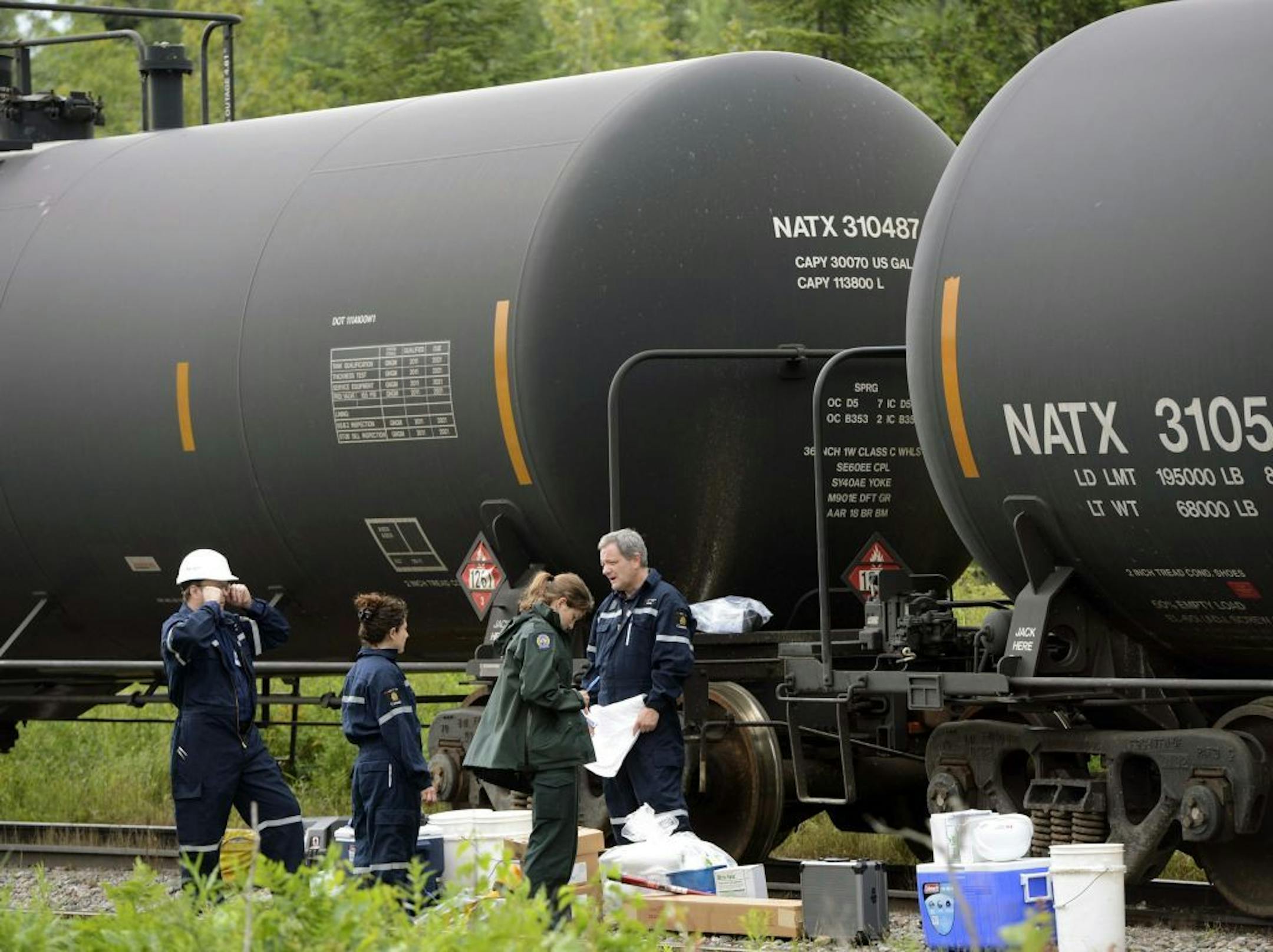 Investigators look over tanker cars that were pulled away from the Lac-M�gantic derailed train inferno, in Nantes, Quebec on Thursday July 11, 2013. Everyone missing in the fiery crash of a runaway oil train in Quebec is presumed dead, police told grieving families, bringing the death toll to 50 in Canada's worst railway catastrophe in almost 150 years.