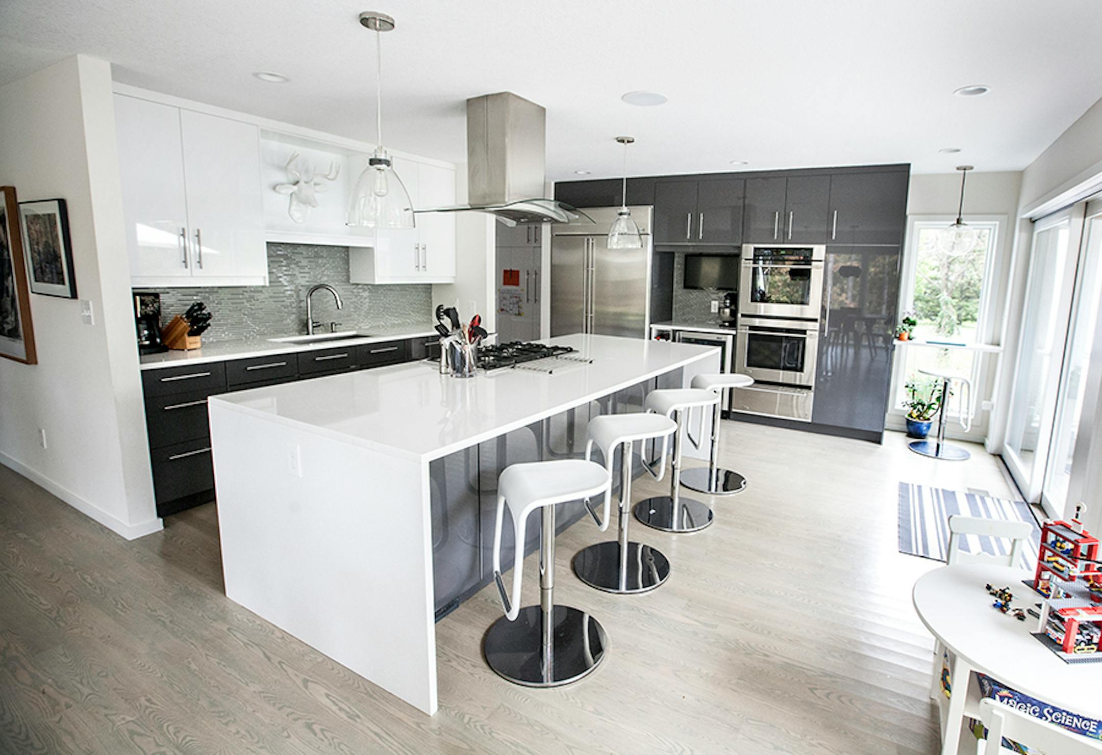 Gray-washed oak floors warm up the reflective charcoal and white surfaces.