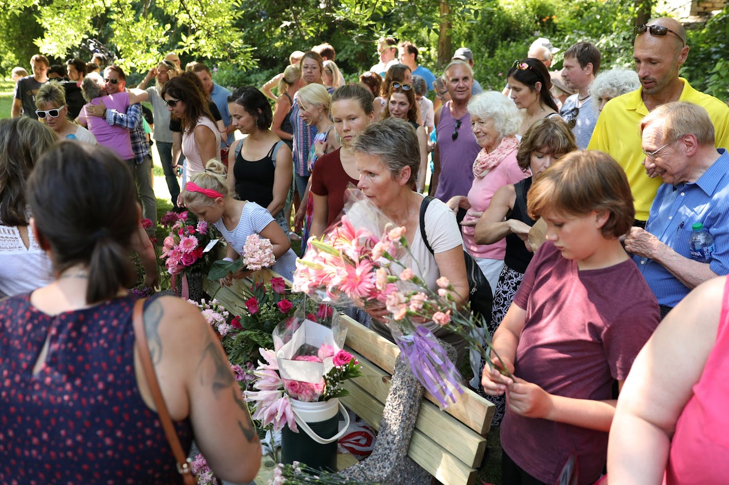 Friends and family that gathered to dedicate a bench to Justine Ruszczyk Damond at Minnehaha Creek between 53rd and 54th streets gathered up flowers to throw into the water in her honor on the one year anniversary of her death.