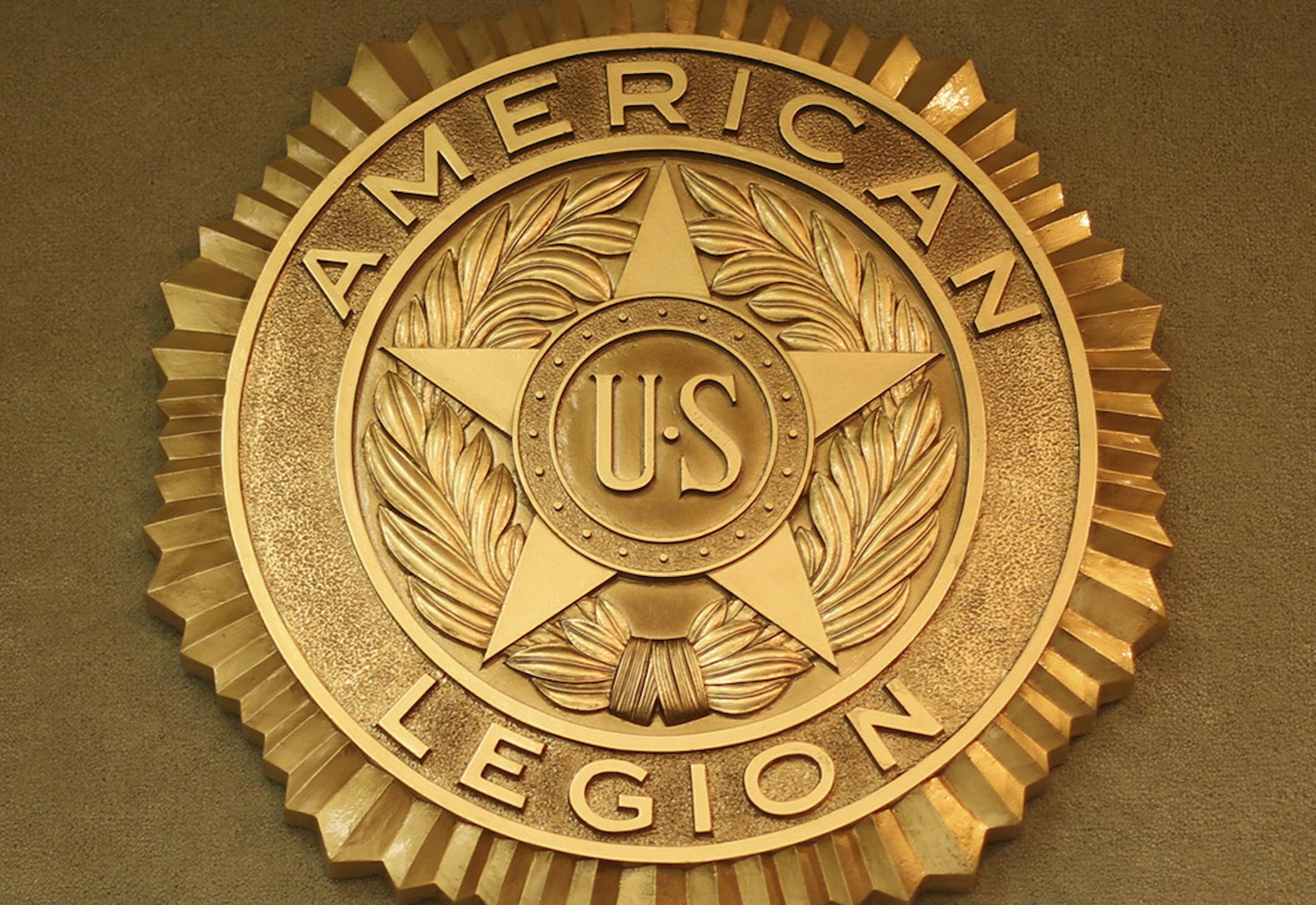 In small cities across the state, American Legion and VFW posts are selling the big buildings they put up back when World War II veterans were joining in droves. Now, outstate posts need to save on expenses in a time of falling membership. The Cambridge American Legion Post sold their building downtown earlier this year. Tuesday night, December 10, 2013, their members held their first meeting in their new, rented storefront. A medallion on the wall behind the flags of each branch of service. ] J