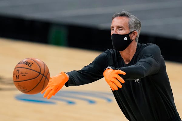 San Antonio Spurs assistant coach Chip Engelland wears a face mask and gloves to protect against the spread of COVID-19 as he helps the team warm up