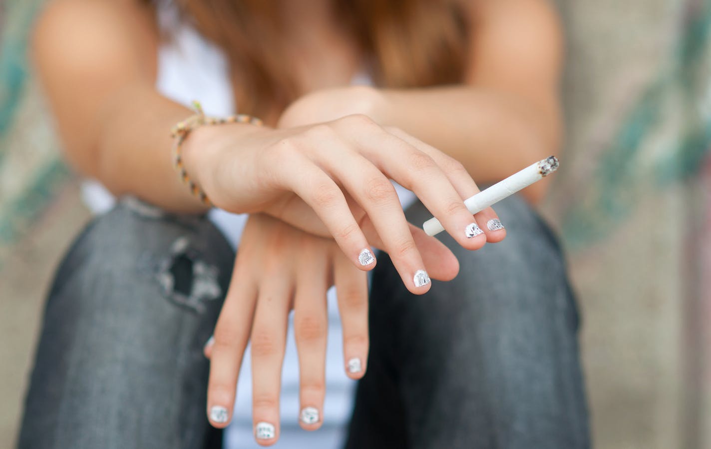 A teen smokes a cigarette.