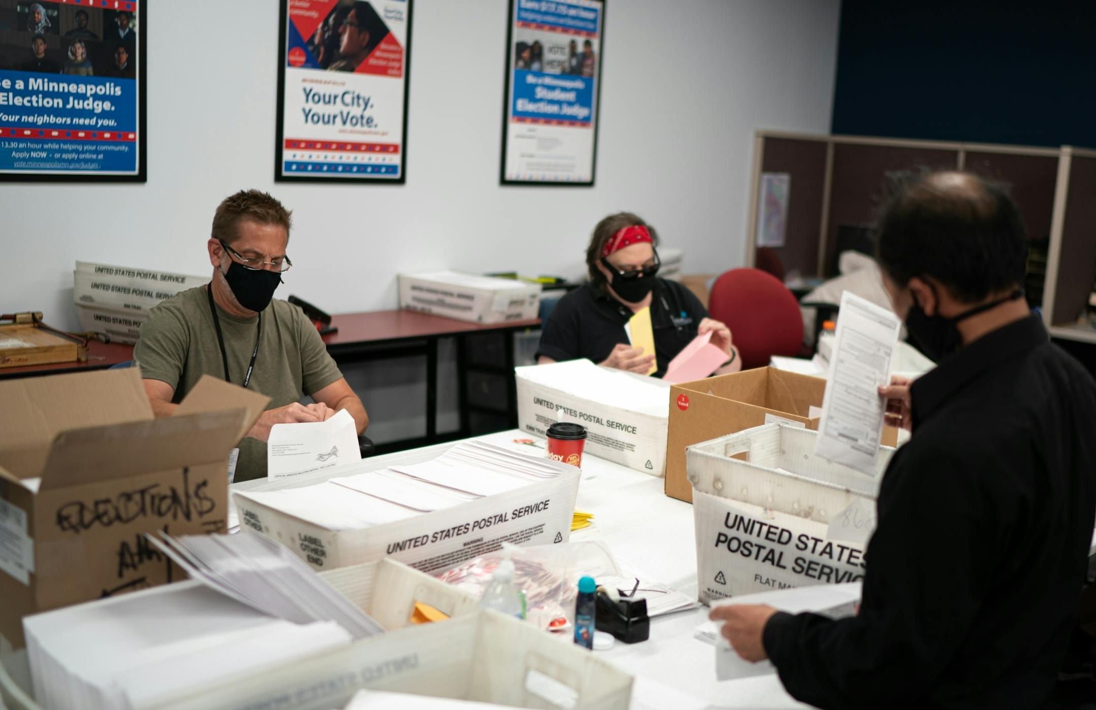 Todd Gallagher and Jazz Thompson prepared mail-in ballot envelopes including an I Voted sticker. Actual ballots are added in the next step where they are checked against names of voters.