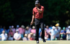 Wearing his traditional Sunday red, Tiger Woods wipes his face on the 15th hole during final round at the Masters in Augusta, Ga.