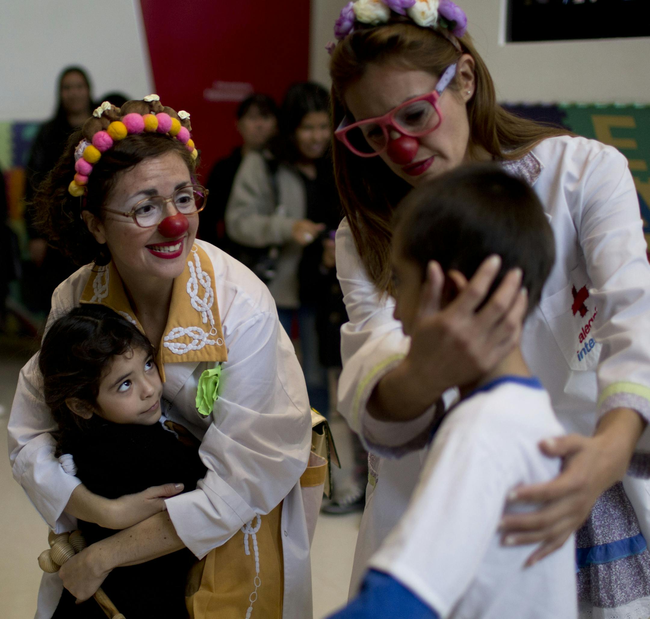 Clowns Romina Amato, left, and Erika Veliz, right, hug children in a waiting room of a pediatric hospital in Buenos Aires, Argentina, Thursday, June 4, 2015. Tapping into the healing power of laughter, a new law in the province of Buenos Aires makes it obligatory that children’s hospitals provide specially trained clowns as part of their health care facilities. (AP Photo/Natacha Pisarenko)