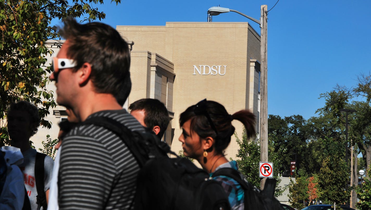 Students gather outside North Dakota State University's Klai Hall after the downtown campus, along with the main campus, was evacuated because of a bomb threat Friday Sept. 14, 2012 in Fargo. Thousands of people streamed off university campuses in Texas and North Dakota on Friday after phoned-in bomb threats prompted evacuations and officials warned students and faculty to get away as quickly as possible. No bombs had been found on either campus by midmorning and it was not clear whether the thr