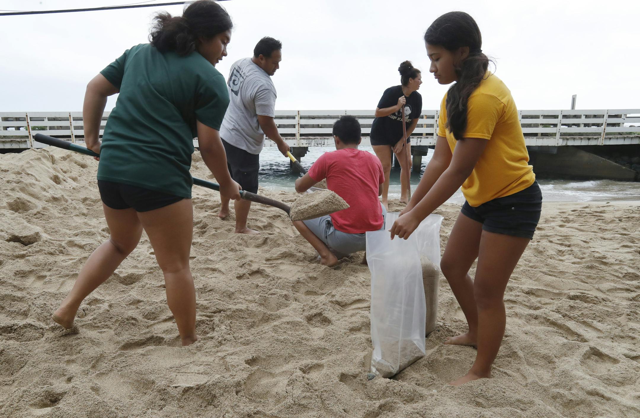 The Keo family assisted the Aubrey family with sandbagging for the preparation of Hurricane Douglas in Hauula, Hawaii, on Sunday, July 26, 2020. Pictured from left-right are, is Keonaona Keo, 17, Aaron Keo, Malu Keo, Amy Aubrey, and Hiwa Keo, 12. (Cindy Ellen Russell/Honolulu Star-Advertiser via AP)