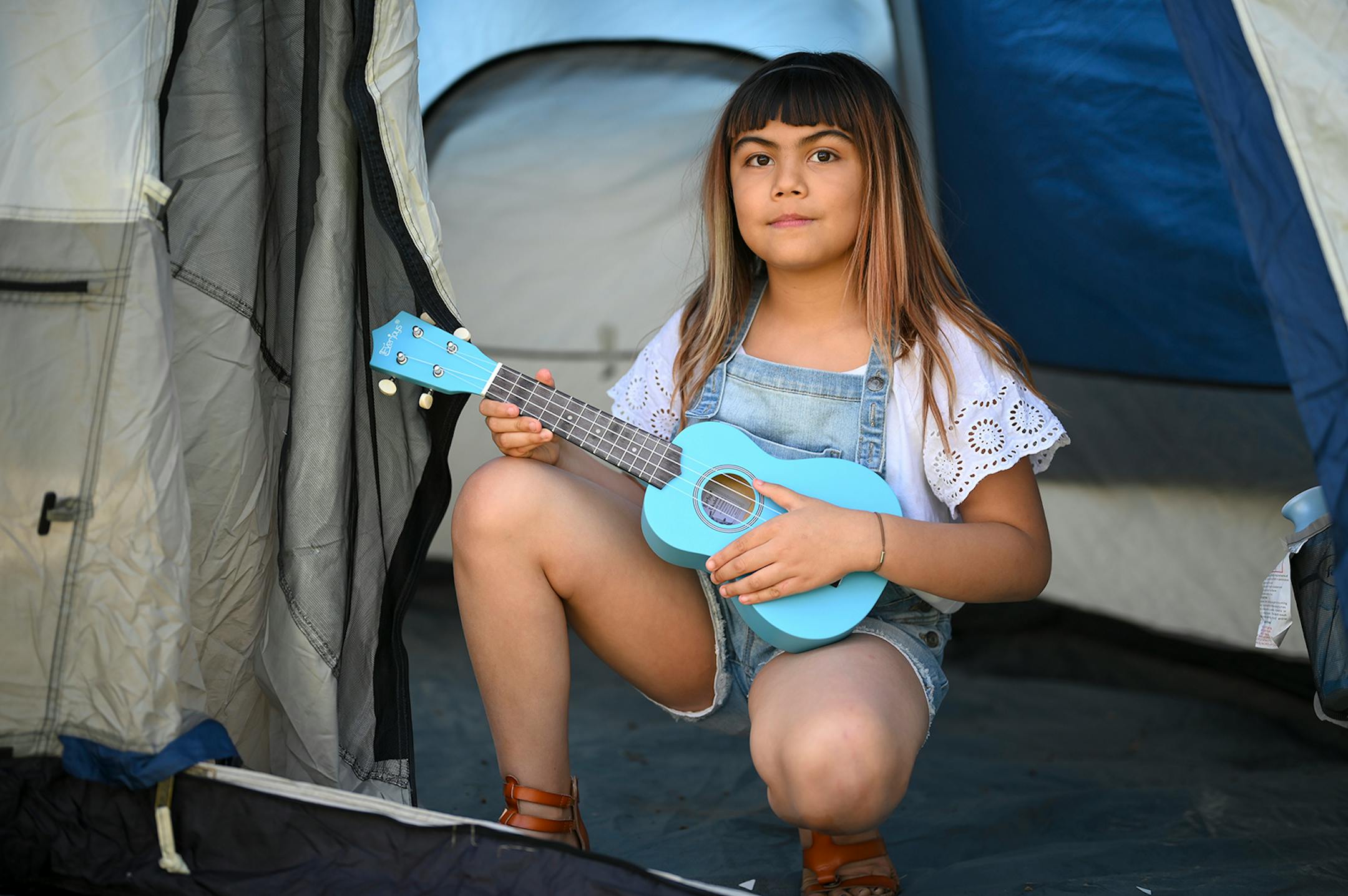 Adella Jonson, 9 , held her ukulele while kneeling for a portrait Thursday in her backyard in Robbinsdale. "It's not the best, it's not the worst," Adella said of life during the pandemic. She's spent her time being creative, writing music, learning how to play the Ukulele and playing with her sister and family.