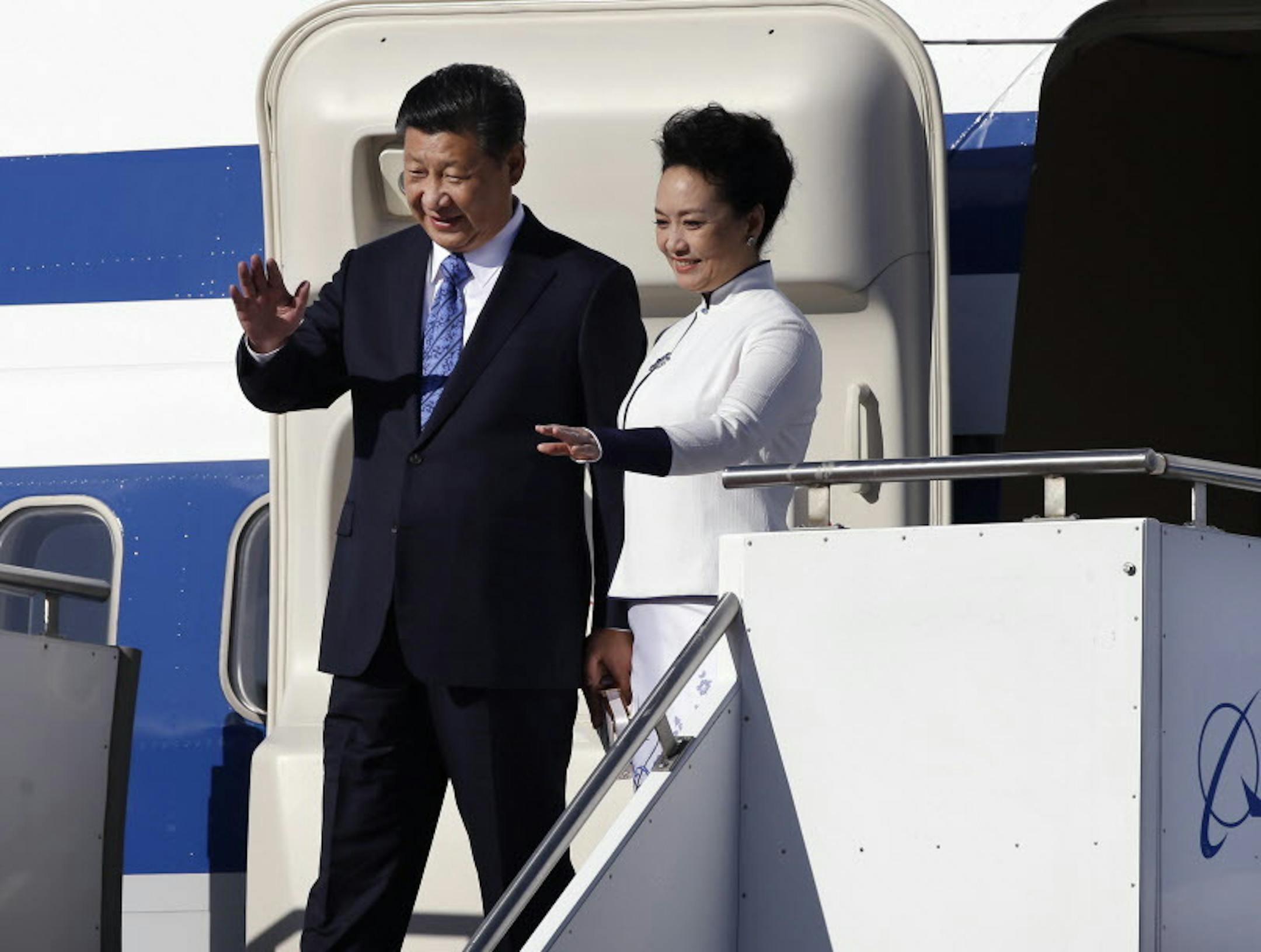 Chinese President Xi Jinping, left, and his wife Peng Liyuan wave on their arrival Tuesday, Sept. 22, 2015, at Boeing Field in Everett, Wash. Xi is spending three days in Seattle before traveling to Washington, D.C., for a White House state dinner on Friday. (AP Photo/Elaine Thompson)