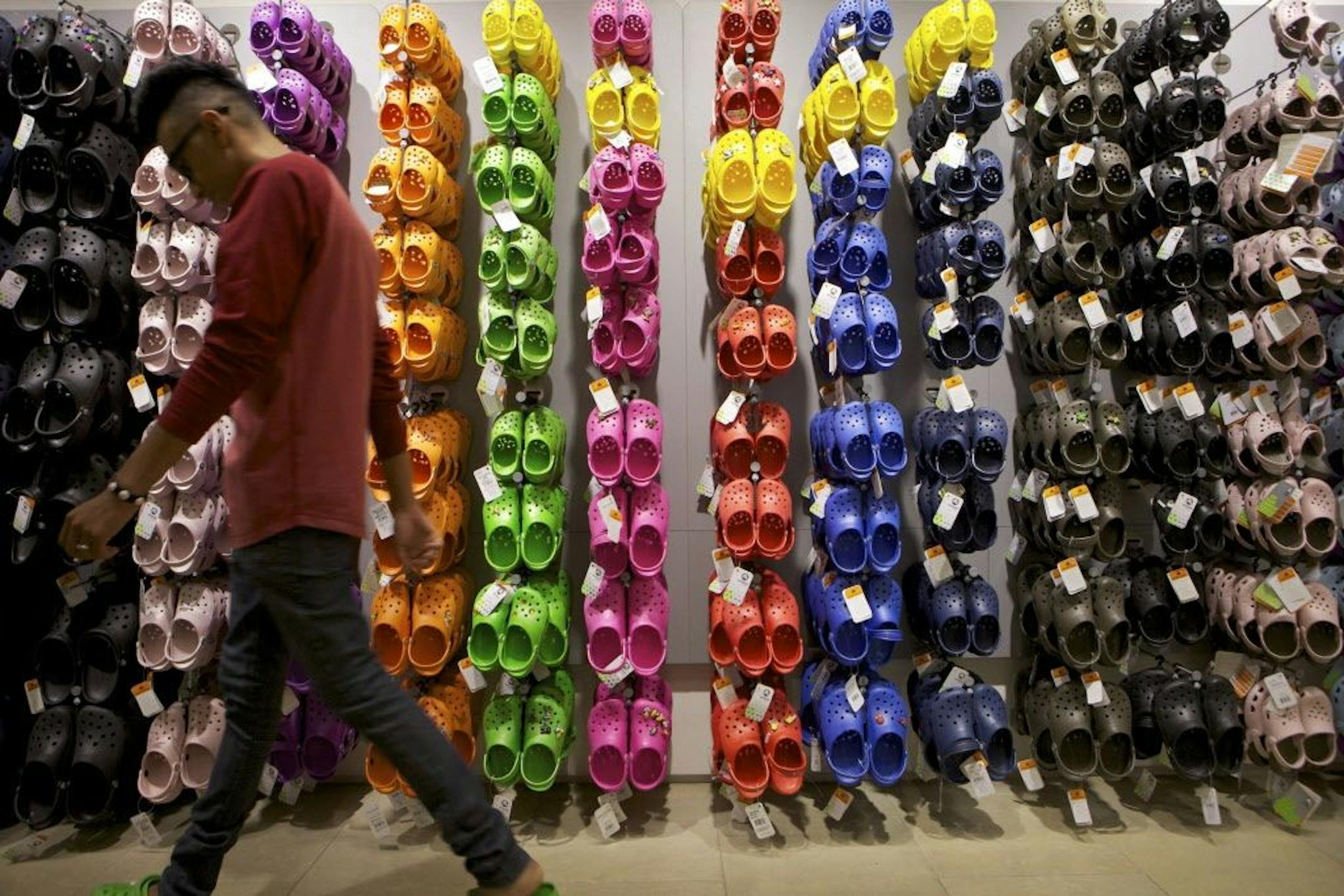 FILE - In this April 9, 2010, file photo, Summett Kumar, a Crocs ambassador, works at Crocs store inside the Beverly Center shopping mall in Los Angeles. Crocs Inc. is closing company-owned manufacturing plants in Italy and Mexico by year's end and replacing its chief financial officer. The company announced the outsourcing of additional manufacturing and the closure of a distribution facility in Mexico Tuesday, Aug. 7, 2018, while reporting a second-quarter profit of $30.4 million, or 35 cents
