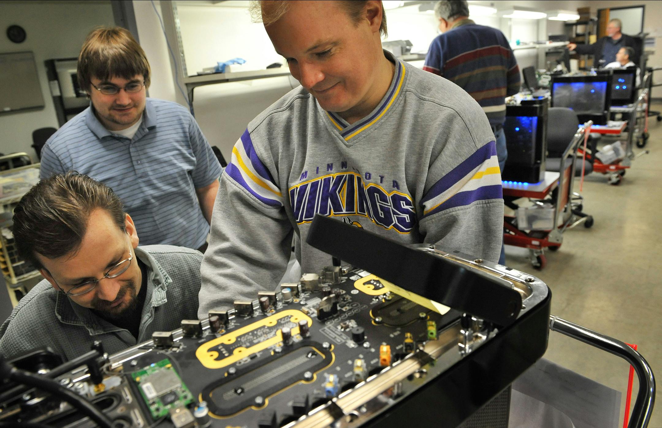Jerry Bernhagen, left, Jim Wilson and Sean Hocum of Hardcore Computer Inc. prepared a Reactor computer for testing by Maximum PC magazine. The computer's key components are submerged in cooling oil, which allows them to be "overclocked" to run at much faster speeds than conventional air-cooled PCs.