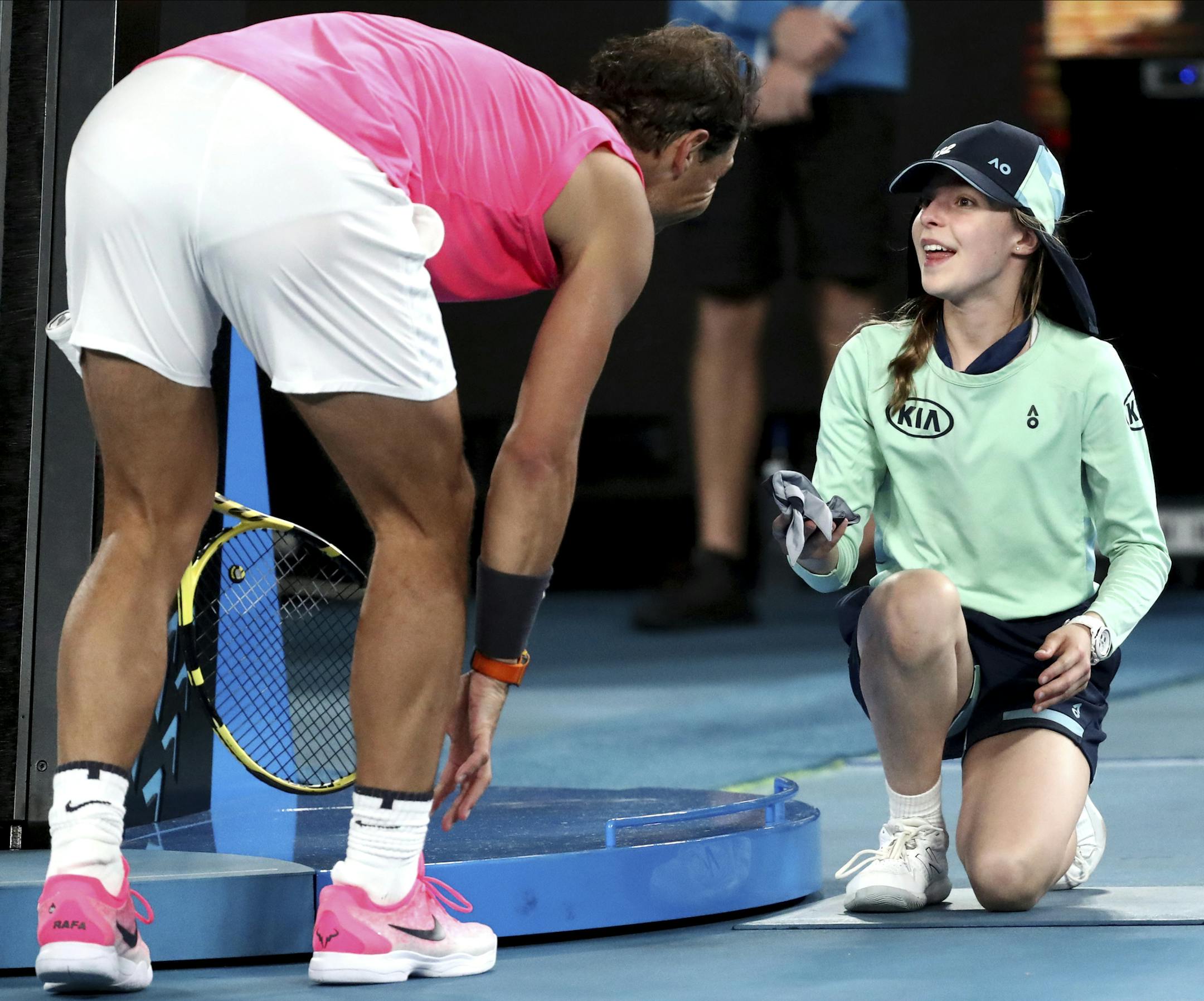 Spain's Rafael Nadal hands a ball girl his bandana after a ball hit her during his second round match against Federico Delbonis of Argentina at the Australian Open tennis championship in Melbourne, Australia, Thursday, Jan. 23, 2020. (AP Photo/Dita Alangkara)