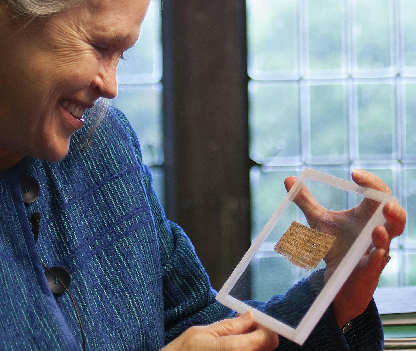 FILE - In this Sept. 5, 2012 file photo released by Harvard University, divinity professor Karen L. King holds a fragment of papyrus that she said is the only existing ancient text that quotes Jesus explicitly referring to having a wife. An article published in the Harvard Theological Review Thursday, April 10, 2014, said new scientific tests suggest the fragment is more likely an ancient document than a forgery. King, an expert in the history of Christianity, said the papyrus probably dates to